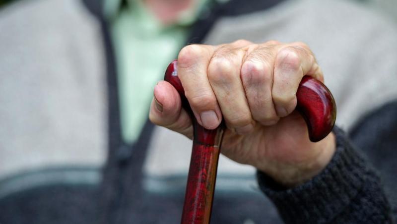 Elderly hand holding wood cane
