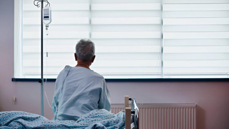 older man in hospital bed. he is looking out the window.